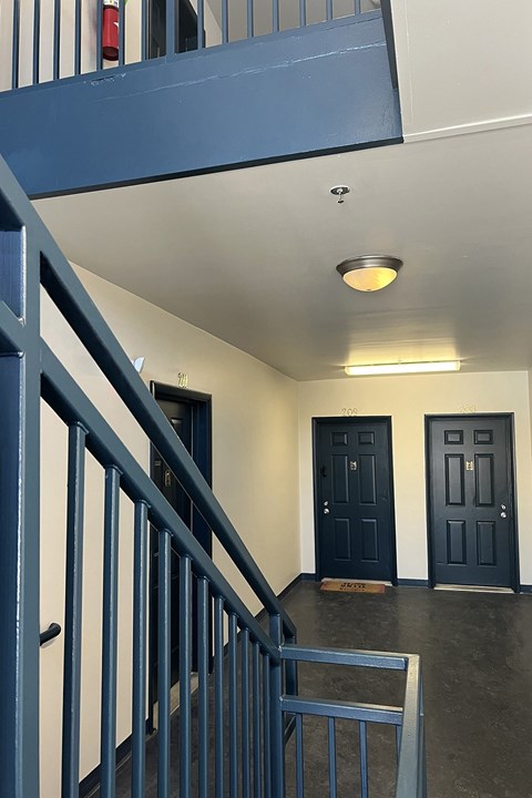 A hallway with blue doors and a metal railing.