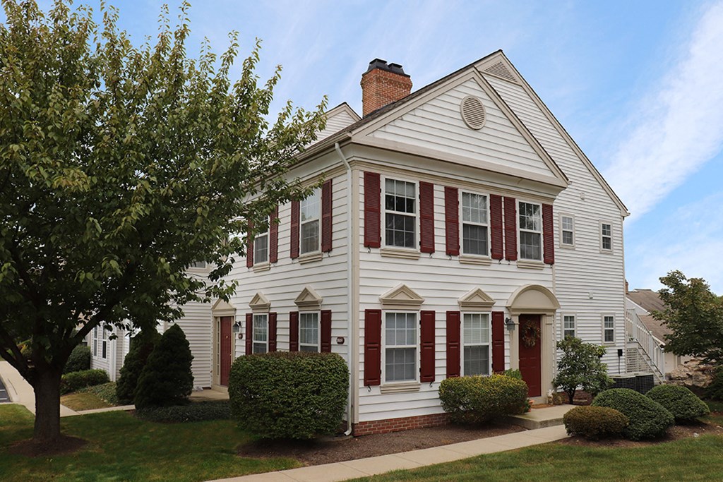 a white house with red shutters and a tree