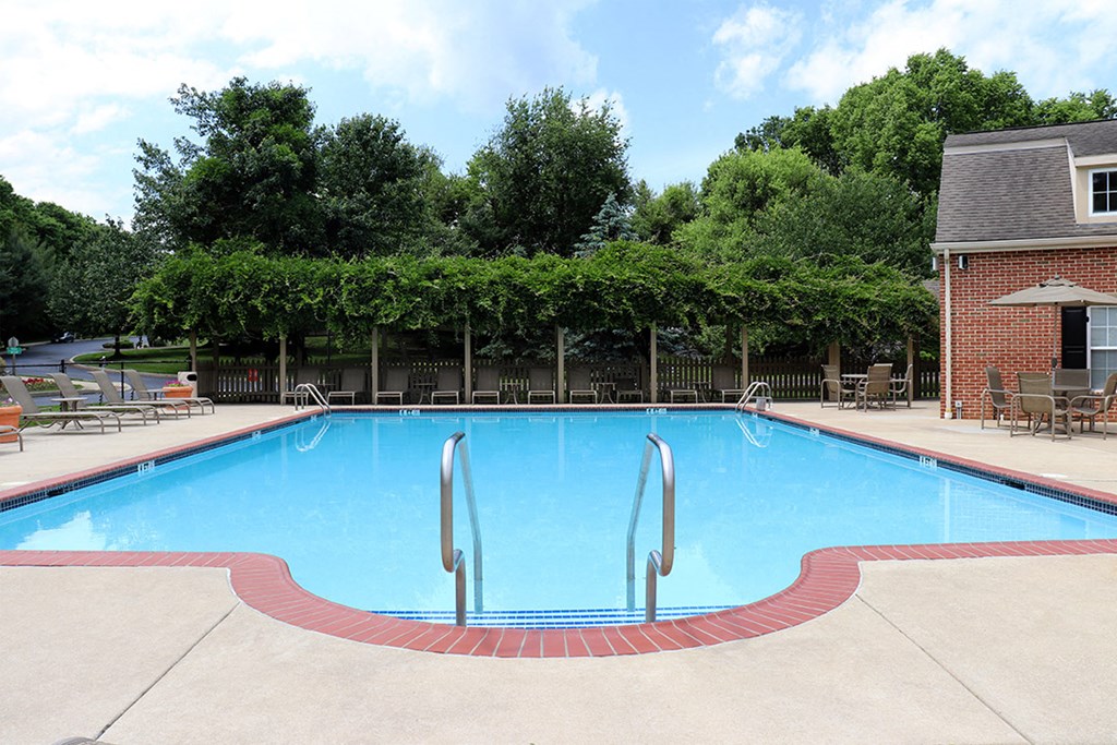 a swimming pool with chairs around it in front of a building