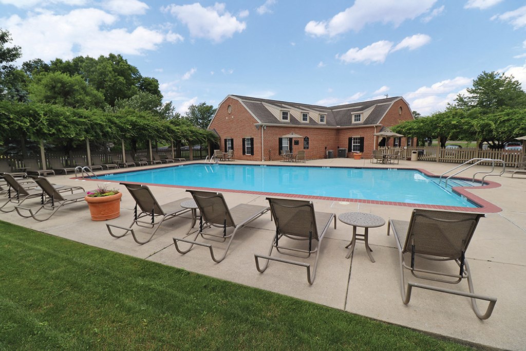 a swimming pool with chairs around it and a building in the background