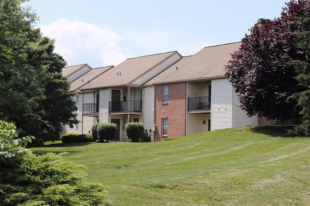 an apartment building on a hill with a green lawn