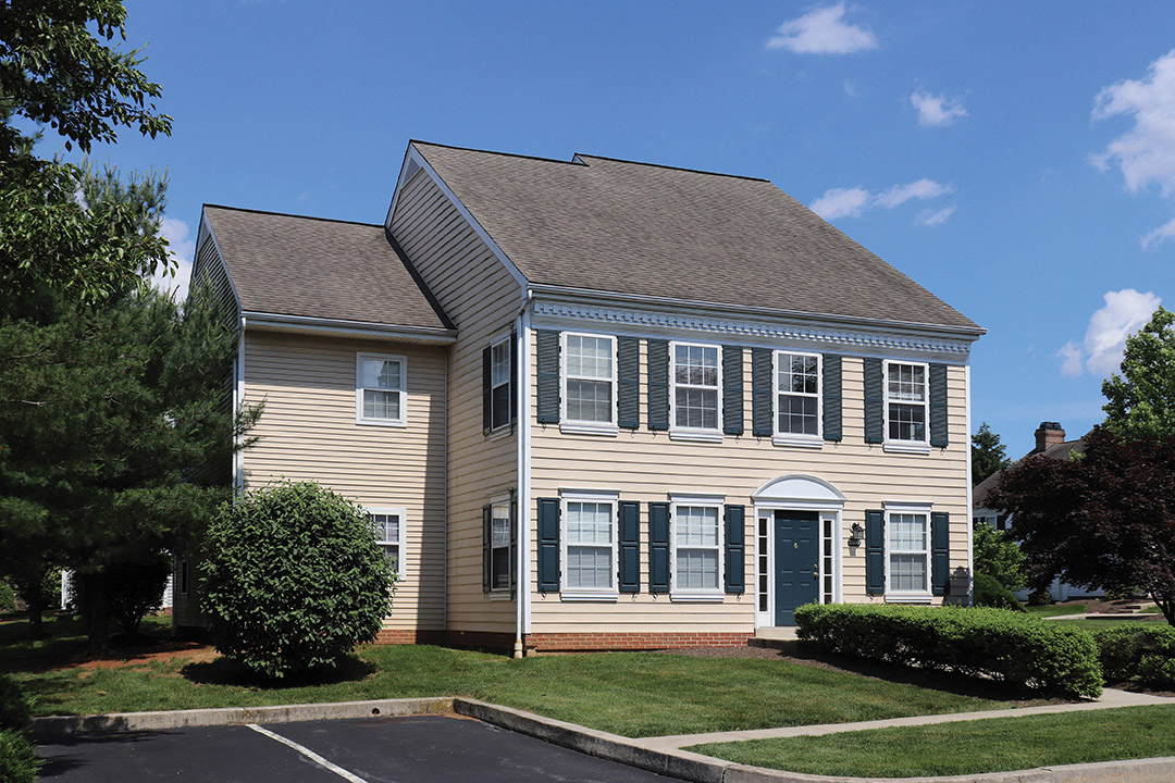 a yellow house with a gray roof and white windows