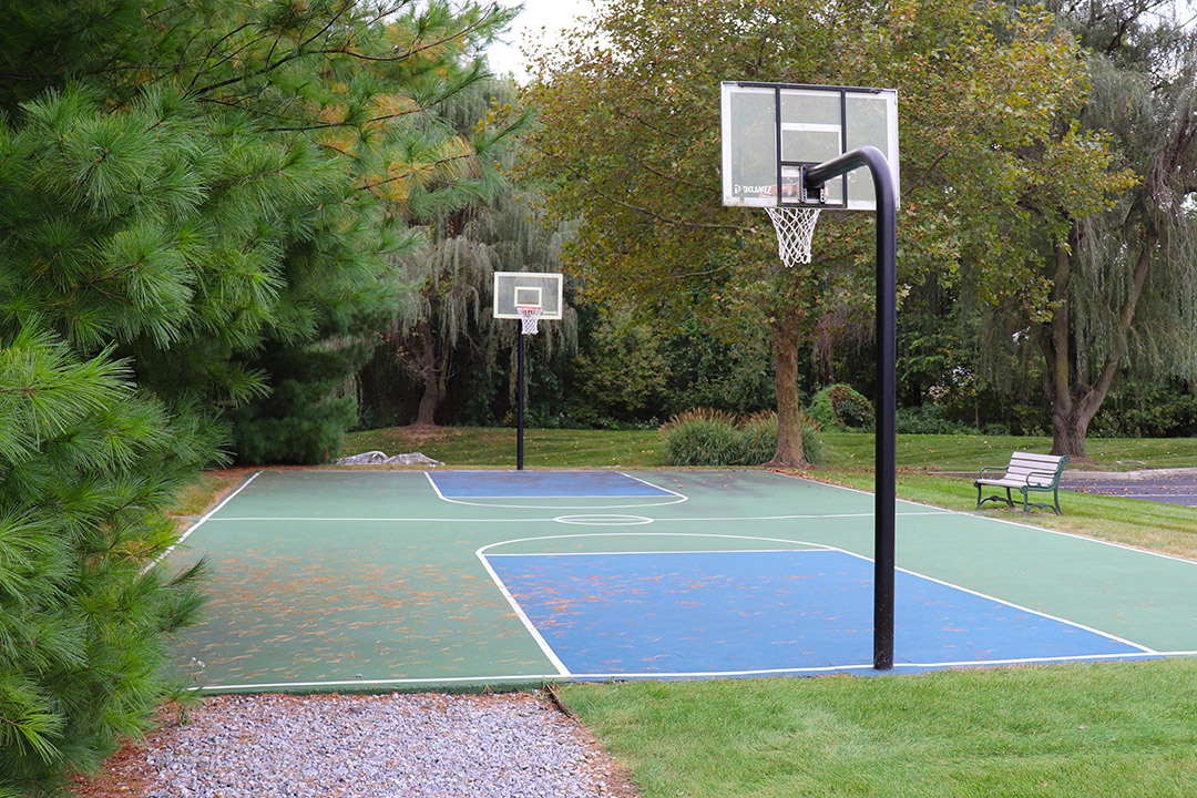 a basketball court in a park with two basketball hoops