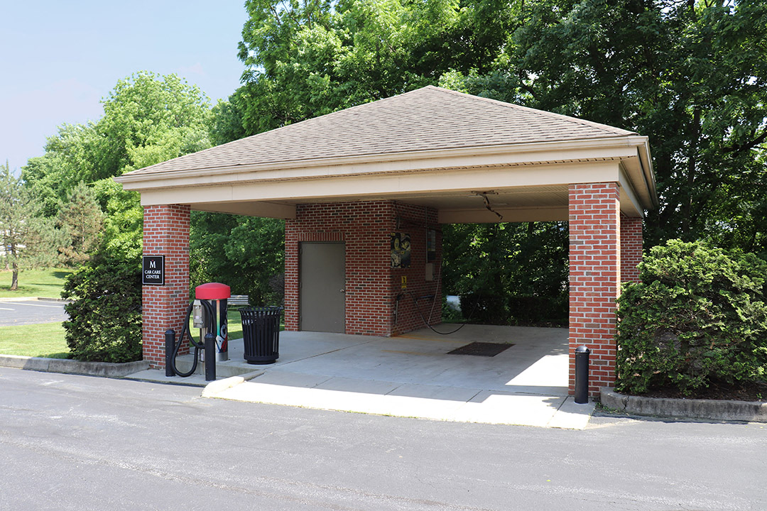 a gas station with a roof and a trash can