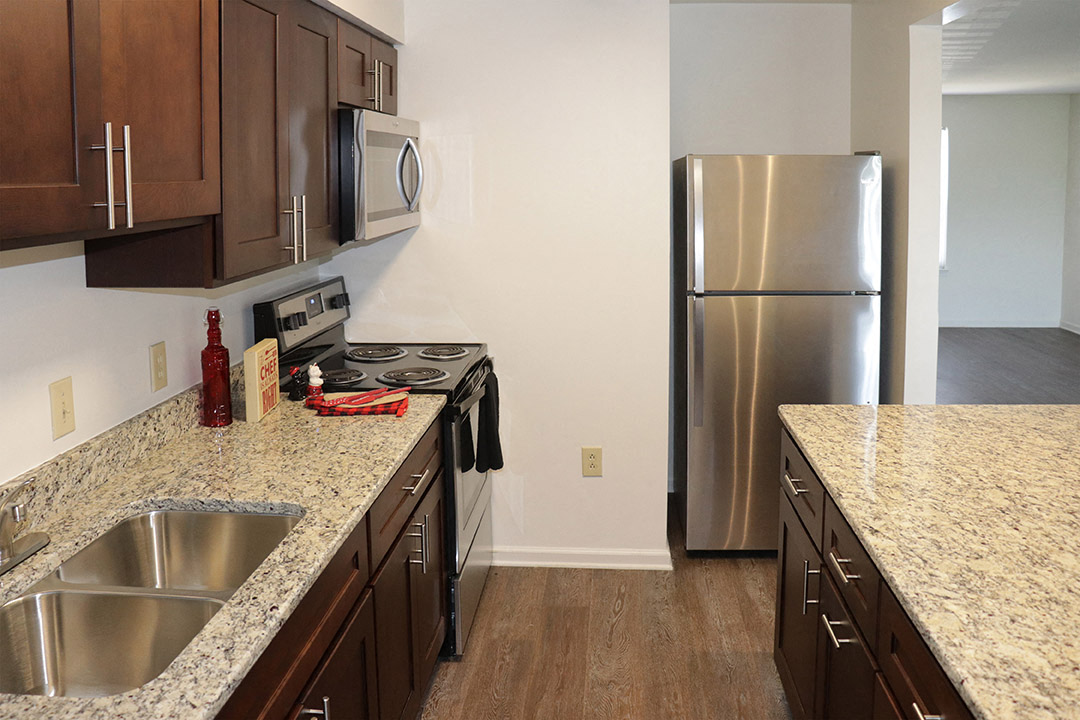 a kitchen with granite counter tops and a stainless steel refrigerator