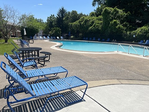 A pool with blue lounge chairs and tables.