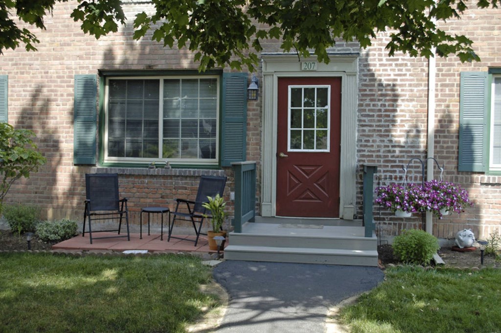 the front of our house with a red door and patio
