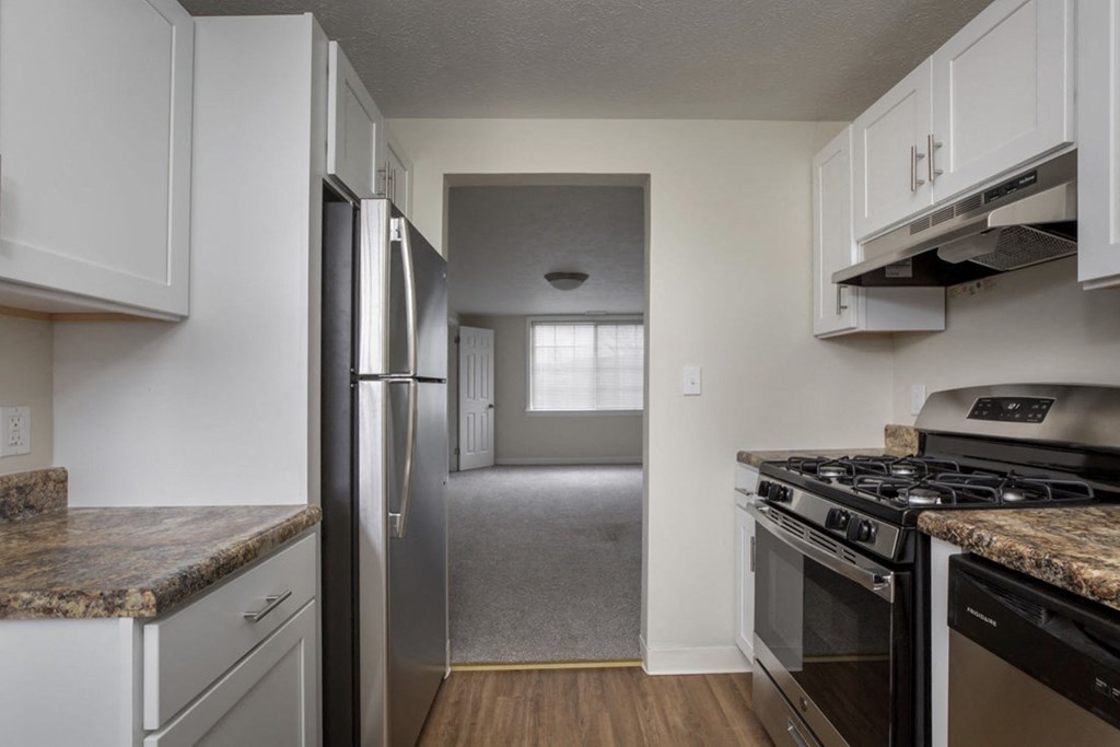 an empty kitchen with white cabinets and stainless steel appliances