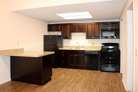 A kitchen with black appliances and wooden cabinets.