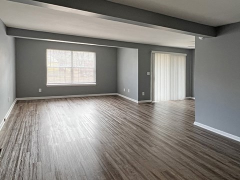 an empty living room with wood floors and a window