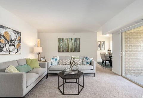 A living room with a grey couch, a coffee table, and a painting on the wall.