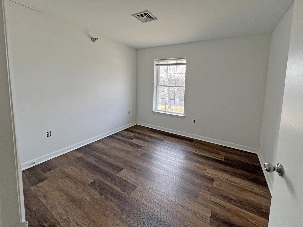 A room with wooden flooring and a window.