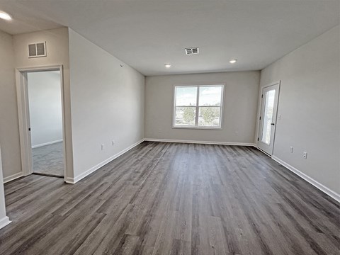 the spacious living room of a new home with white walls and wood flooring