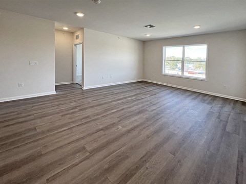 an empty living room with wood floors and a window