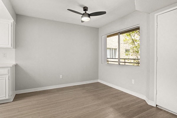 an empty living room with a ceiling fan and a window