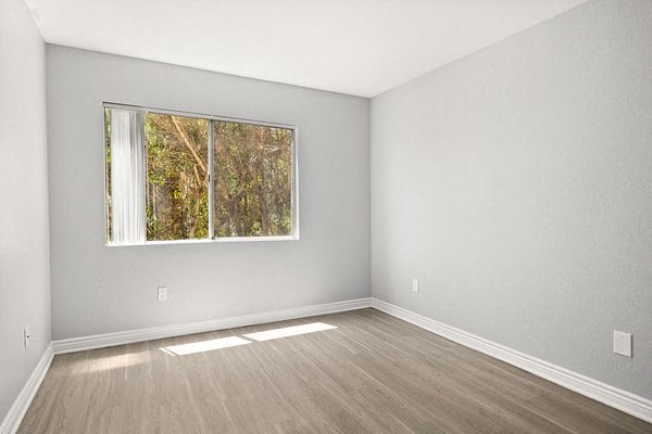 an empty room with wooden floors and a window