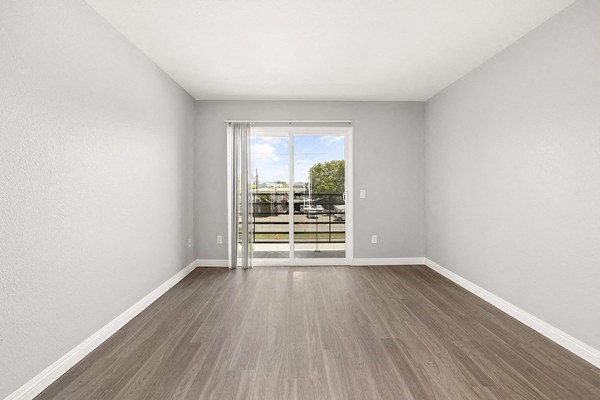 an empty living room with a door to a balcony