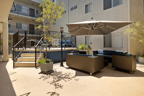 a patio with couches and an umbrella in an apartment building