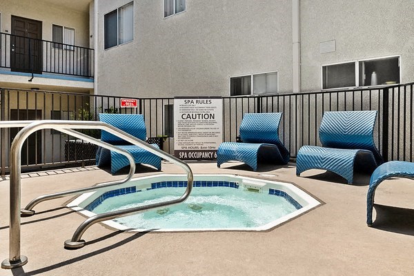 a jacuzzi pool with blue chairs and a black fence