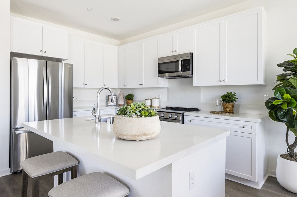 a white kitchen with a large island and stainless steel appliances
