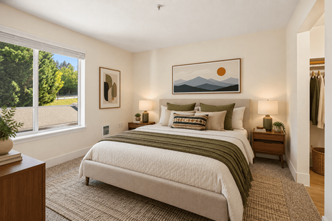 A bedroom with a large bed and a painting of a sunset on the wall.