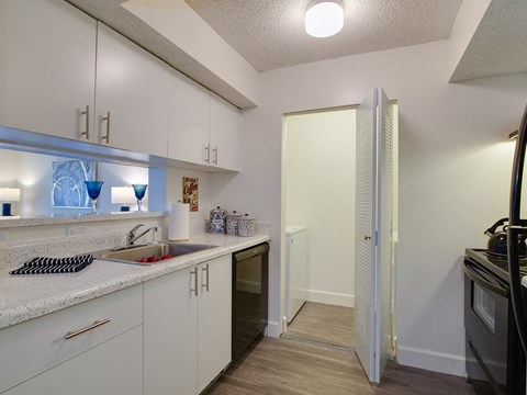 a kitchen with white cabinets and a door to a hallway