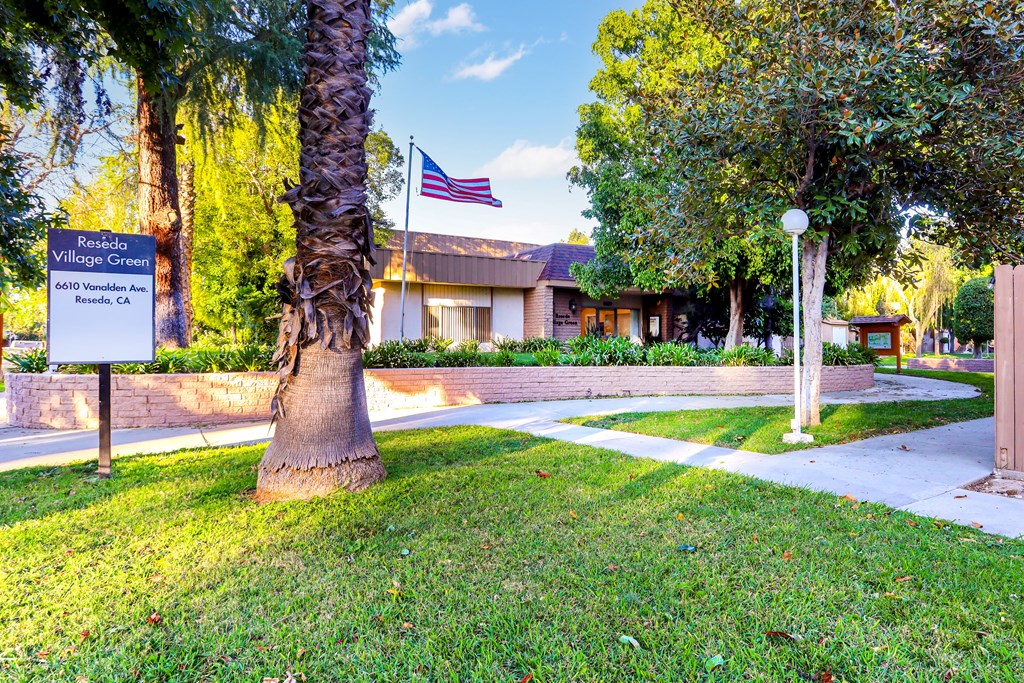 an flag flies in front of a building with a sidewalk and a tree