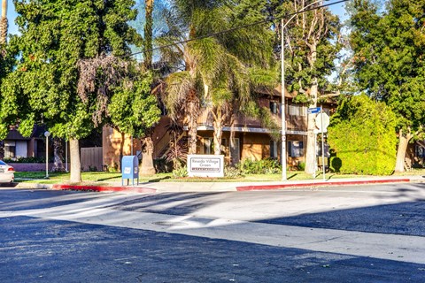 an empty street in front of a building with palm trees