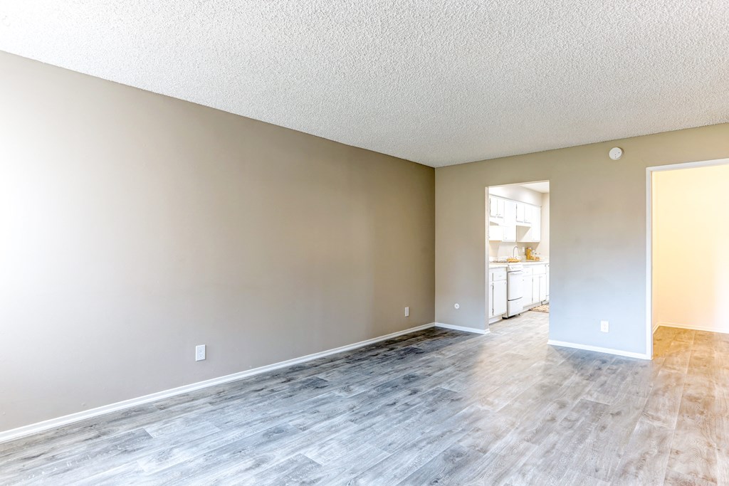 an empty living room and kitchen with wood flooring