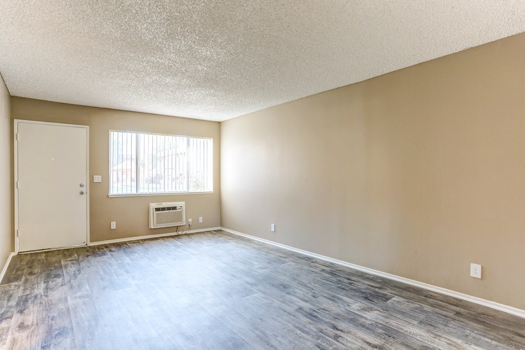an empty living room with wood floors and a window