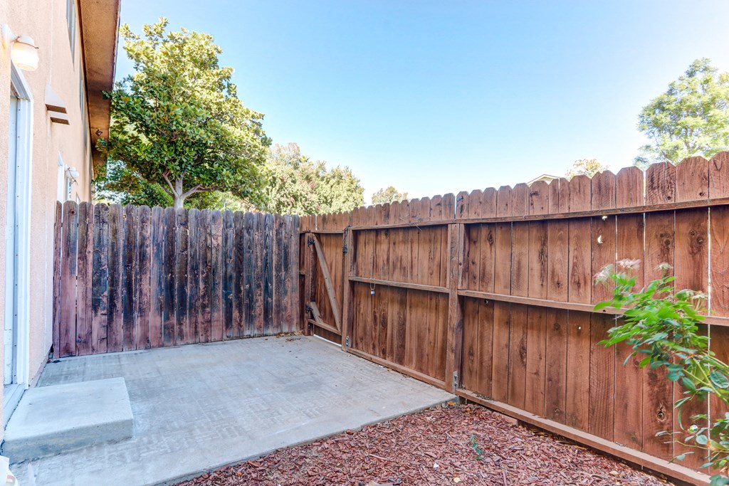 a backyard with a wooden fence and a concrete patio