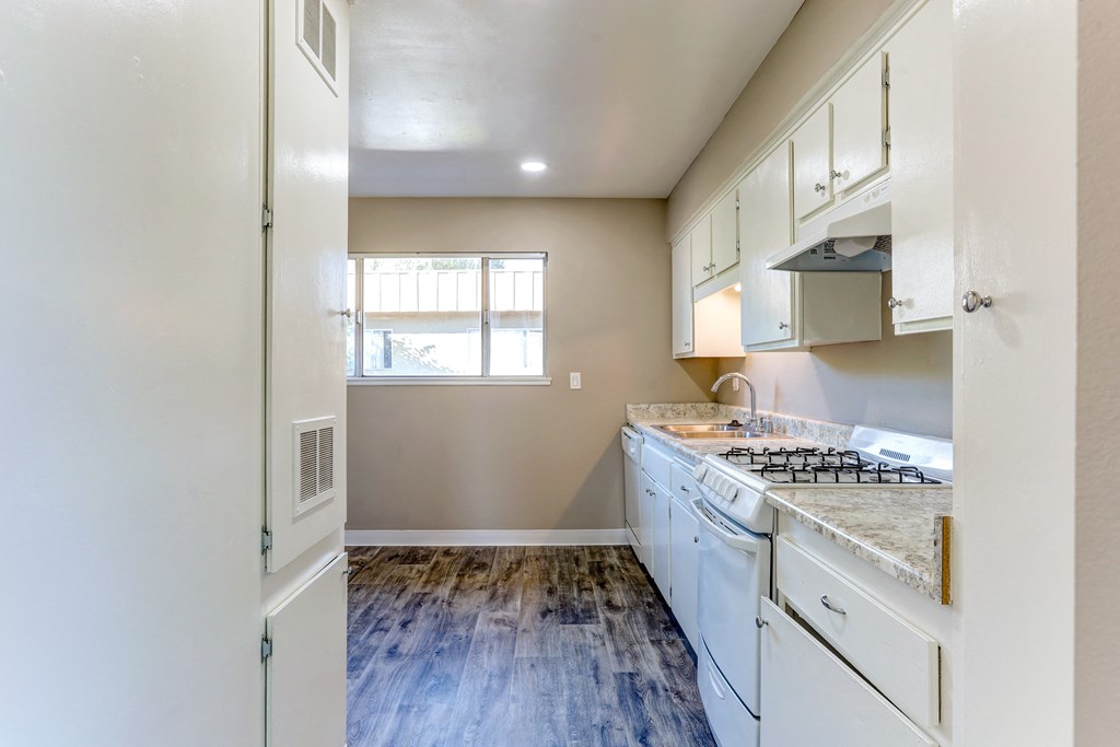 an empty kitchen with white appliances and a window