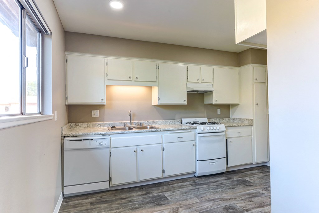 an empty kitchen with white appliances and white cabinets