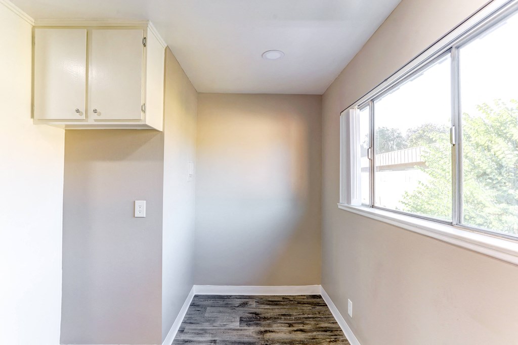 an empty room with a large window and white cabinets