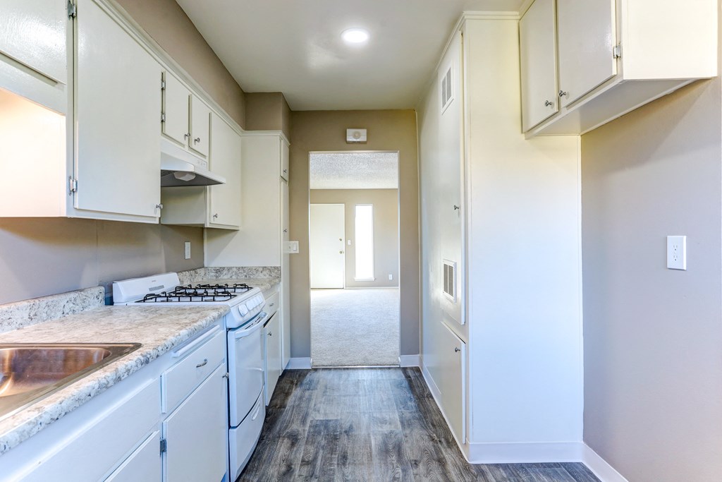 an empty kitchen with white appliances and white cabinets