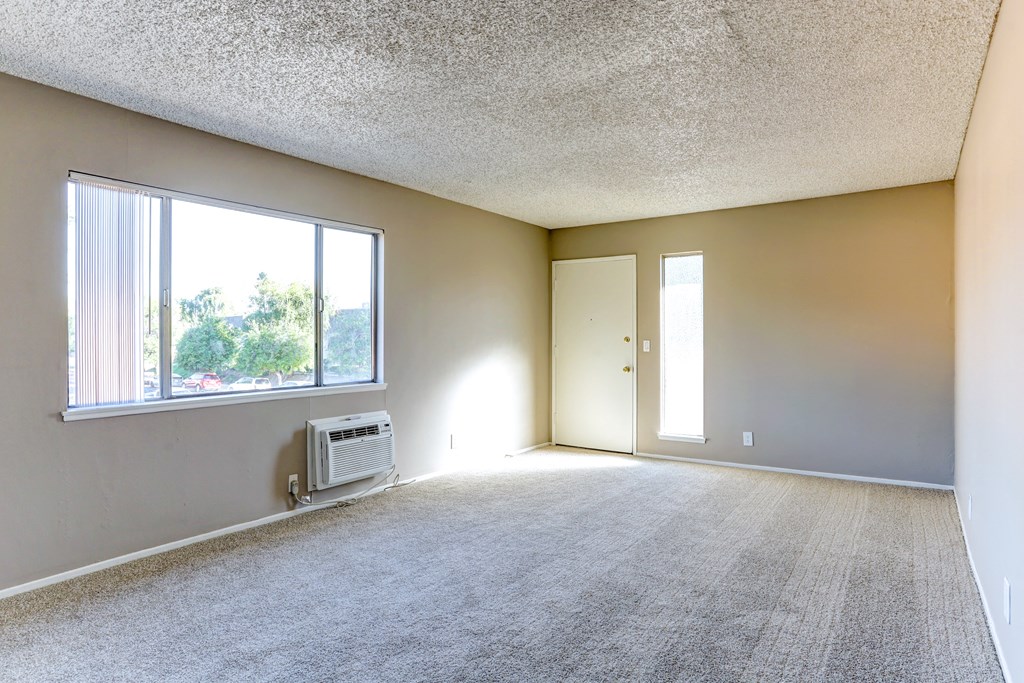 the living room of an empty apartment with a large window