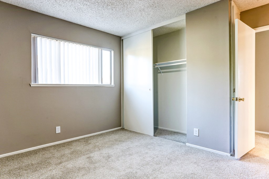 an empty bedroom with a closet and a window