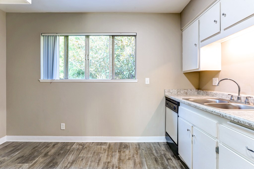 an empty kitchen with white cabinets and a window