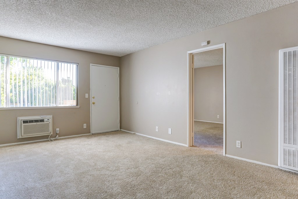 an empty living room with a window and a door to a hallway