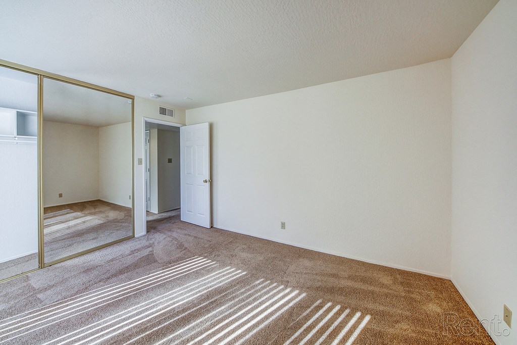 a bedroom with a large mirror and a carpeted floor