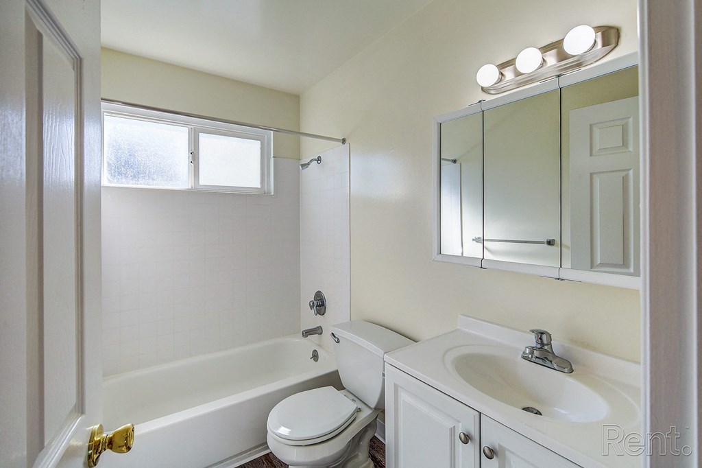 a bathroom with a white sink and toilet and a tub with a shower curtain