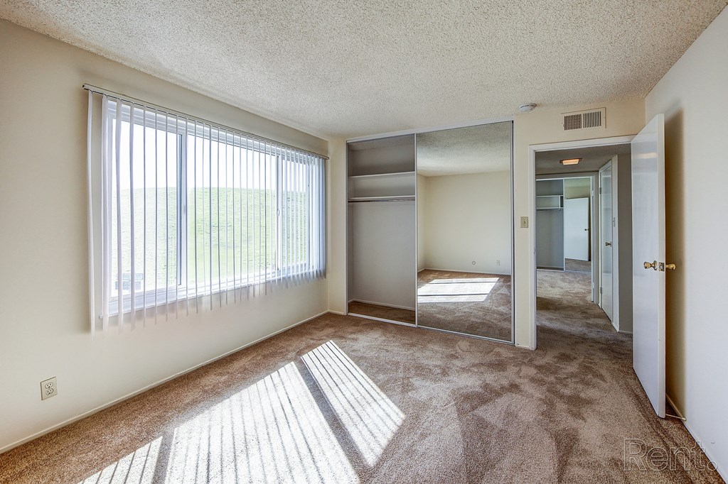 a bedroom with a large window and carpeted flooring