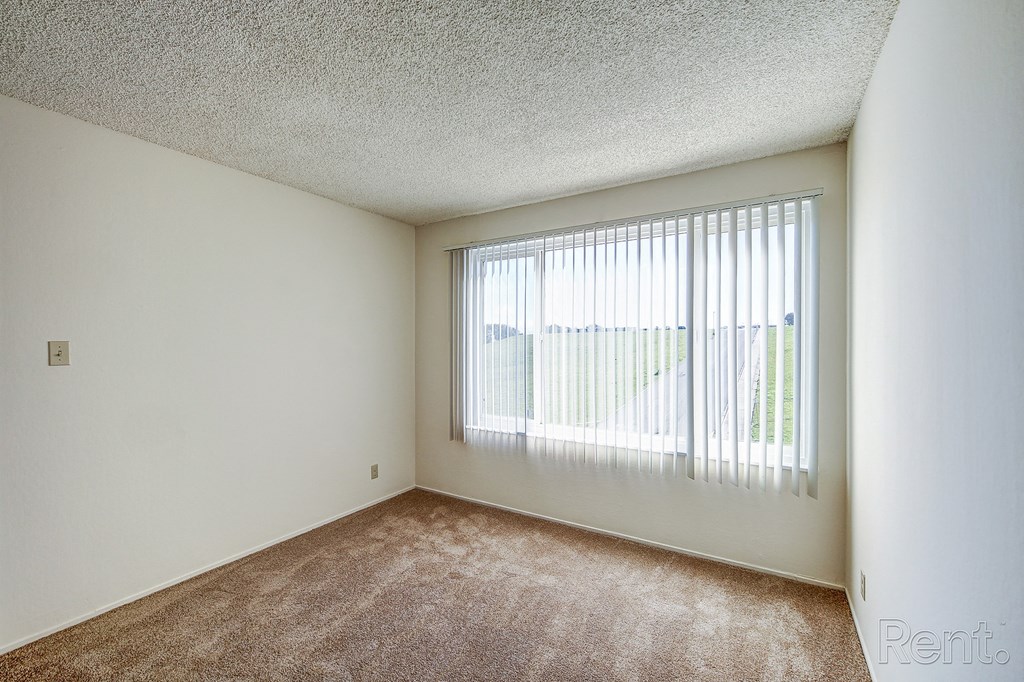 a bedroom with a large window and beige carpet