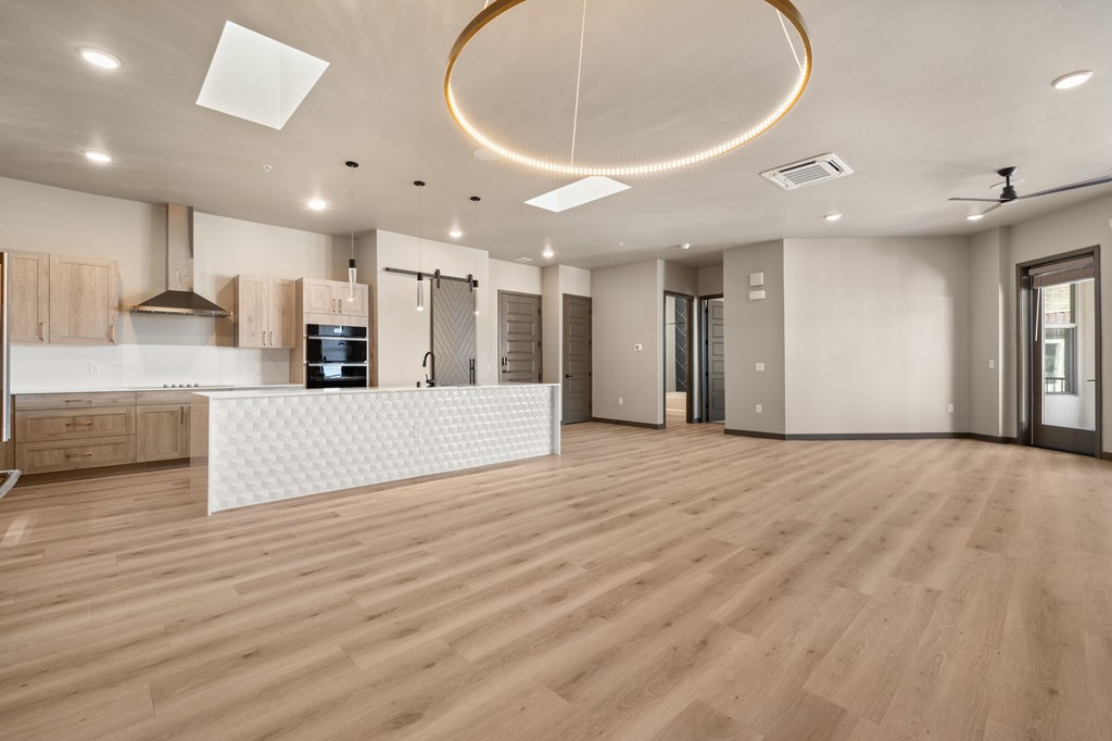A spacious kitchen with wooden floors and a white counter.