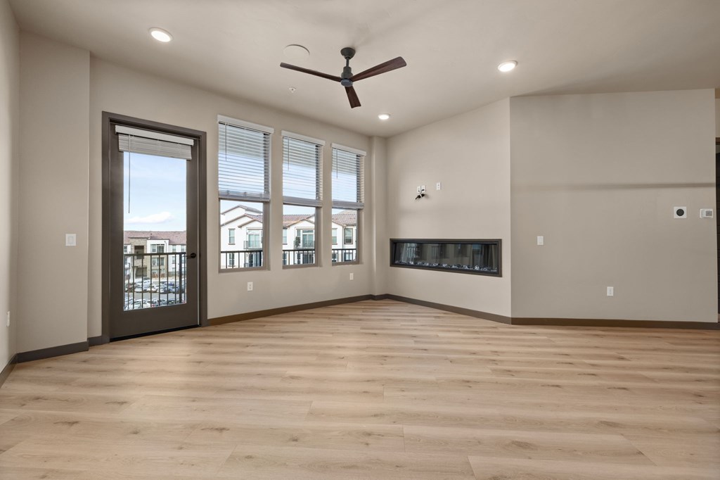 A spacious room with a ceiling fan and large windows.
