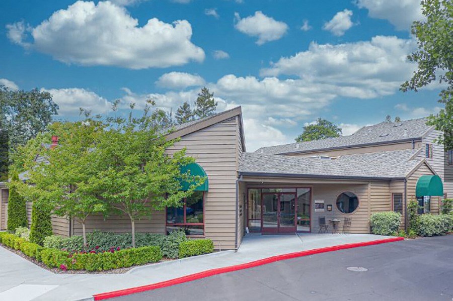 Leasing office building with a gray roof and a tree in front of it
