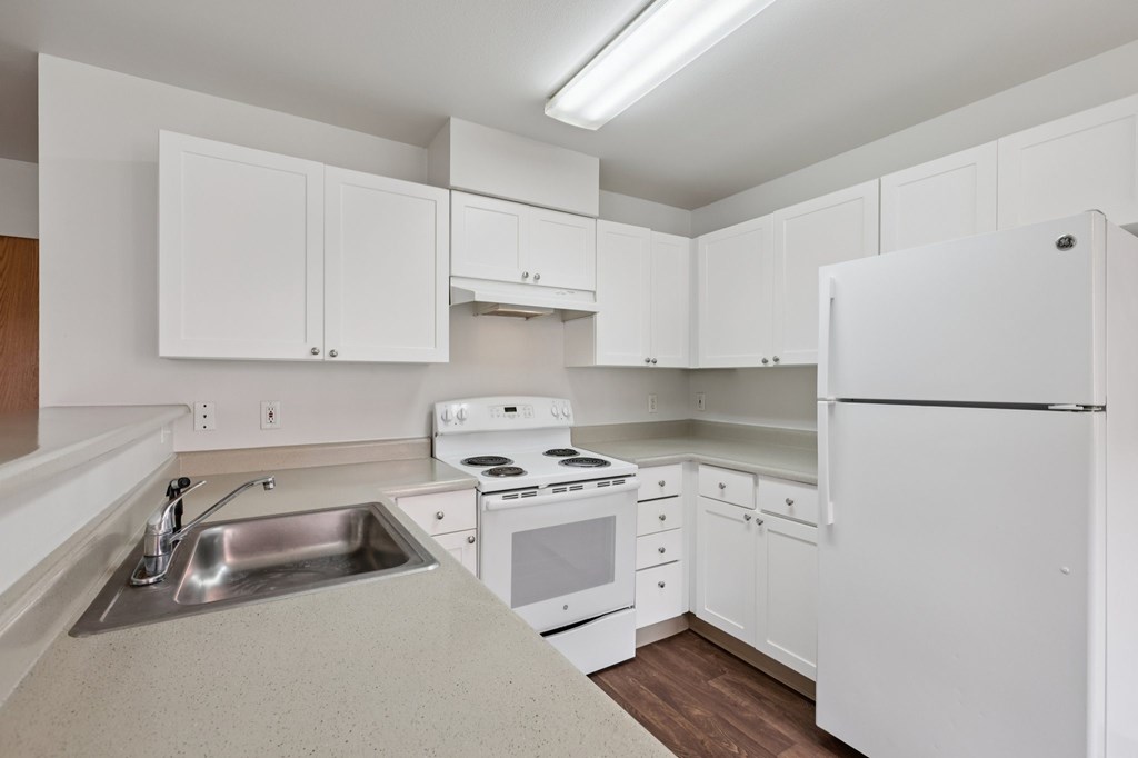 A white kitchen with a sink, stove, and refrigerator.at The Timbers by Vintage, Arlington