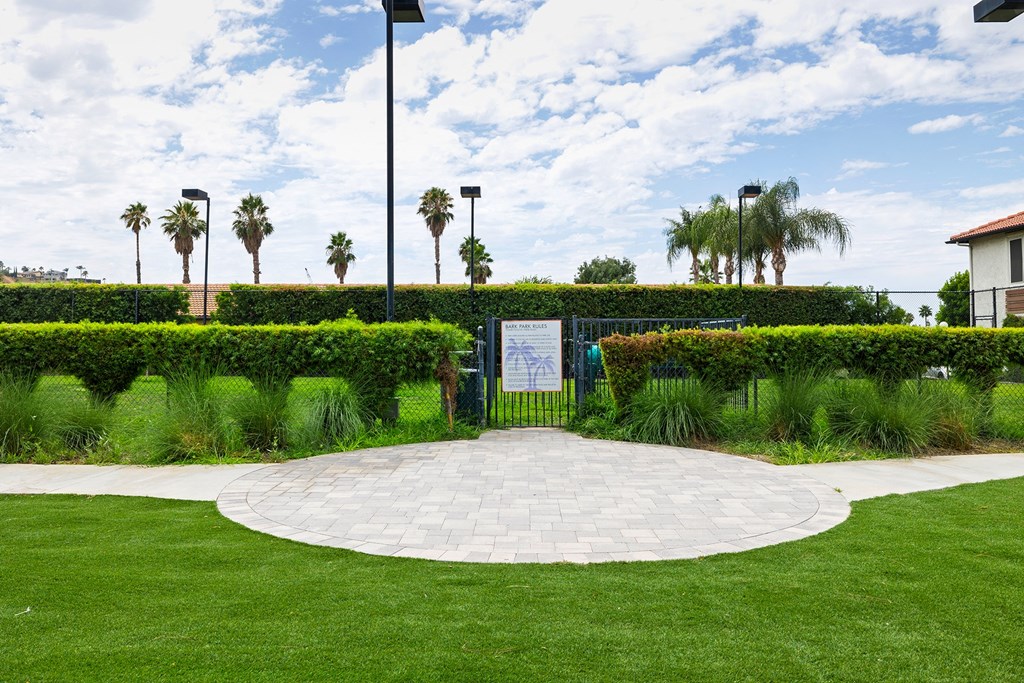 a grassy area with a paver walkway and a sign in the middle of it