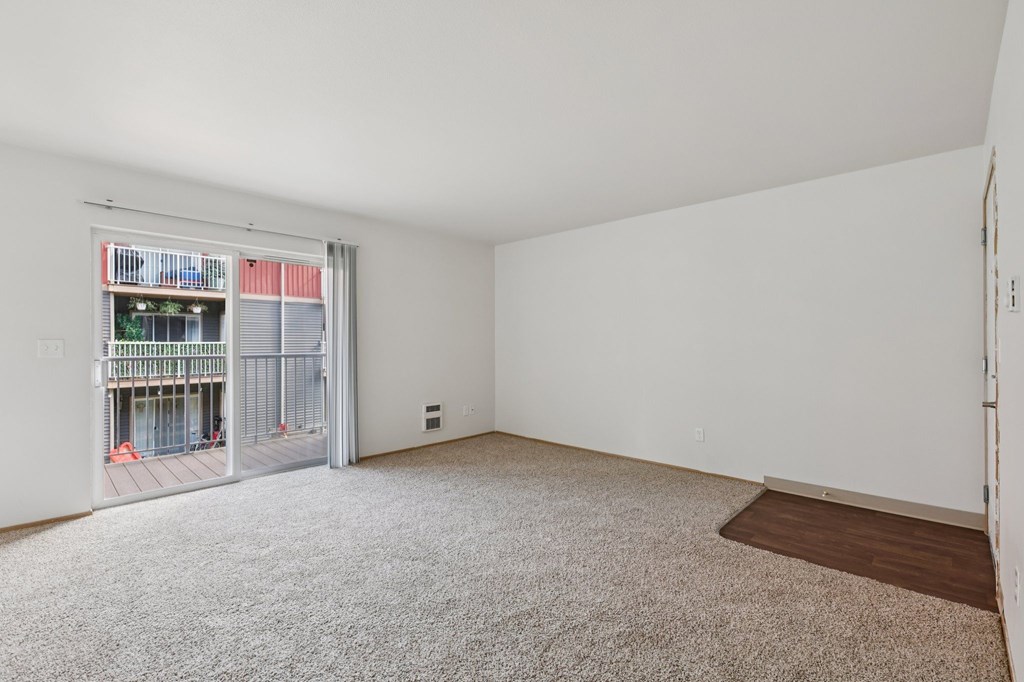 A room with a carpeted floor and a sliding glass door leading to a balcony.at The Timbers by Vintage, Arlington, WA