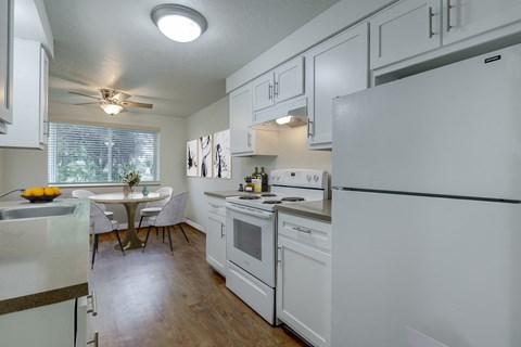 a kitchen with white cabinets and appliances and a dining room with a table and chairs